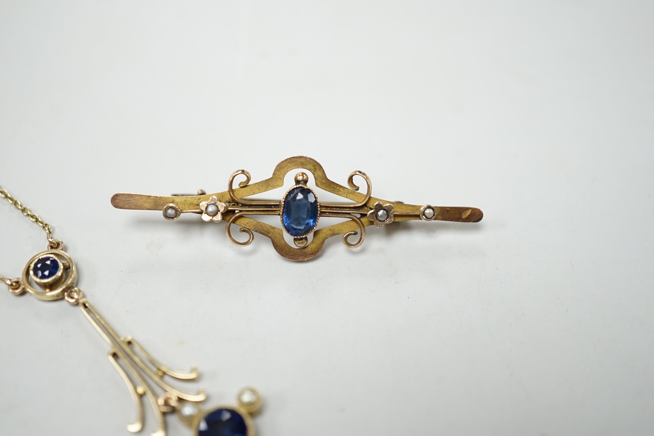 An Edwardian 15ct gold, sapphire and seed pearl set drop pendant necklace, overall 52cm, gross weight 4.5 grams and one other yellow metal and gem set bar brooch.